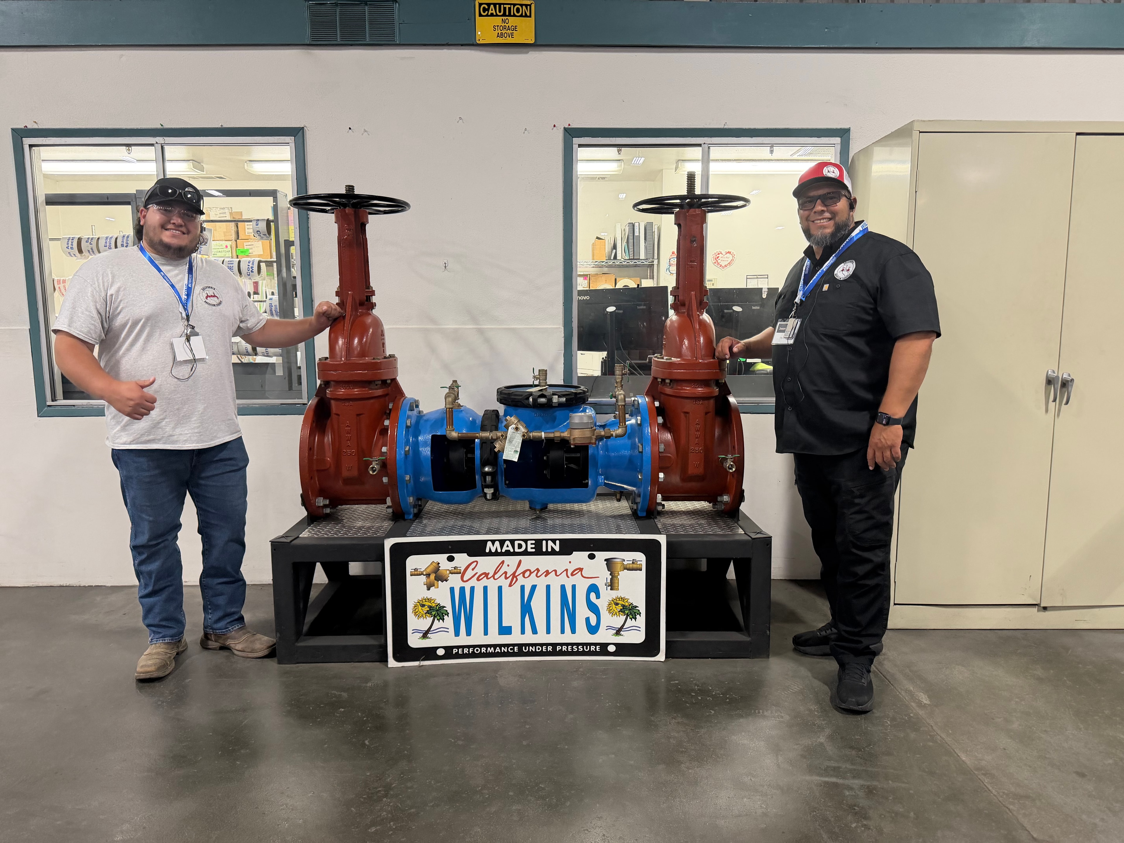 Two California Backflow Services technicians posing with industrial valve equipment